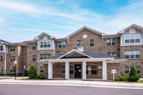 A large brick building with a covered entrance and a circular window above the door at Bickerstaff Crossing Apartments, Henrico, VA, 23231