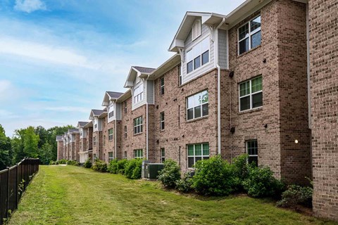 A row of brick apartment buildings with green lawns in front. at Bickerstaff Crossing Apartments, Henrico, VA