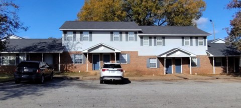 A two-story house with a white car parked in front.