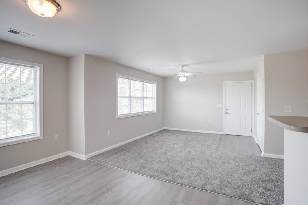 A spacious room with a rug on the floor and a ceiling fan.