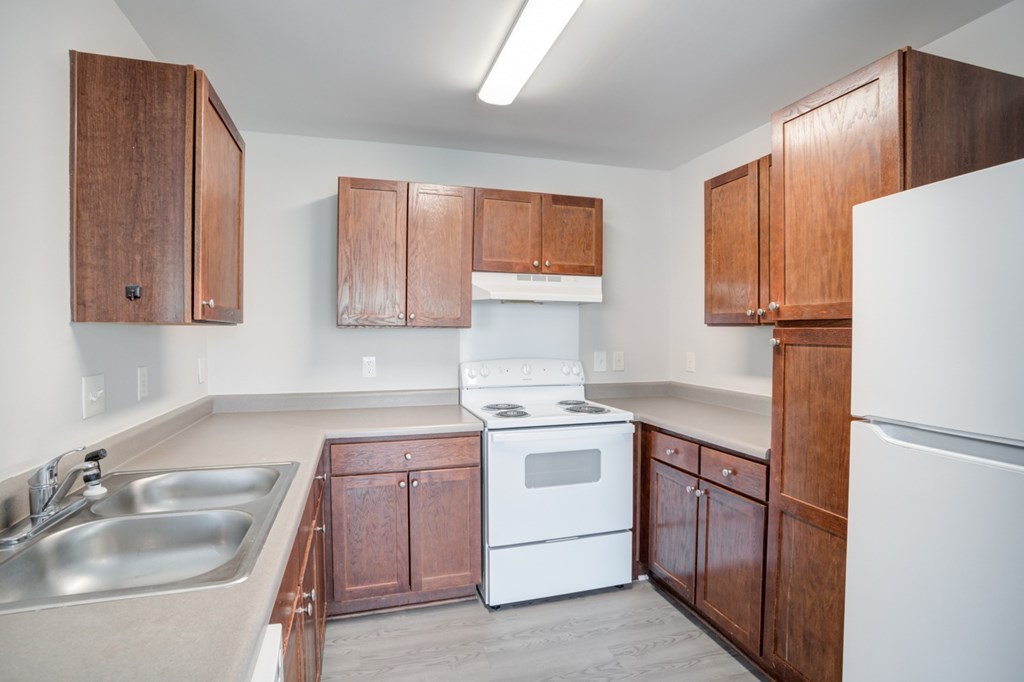 A kitchen with white appliances and wooden cabinets.