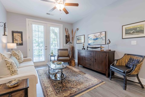 A living room with a white sofa, a glass coffee table, and a wooden cabinet.