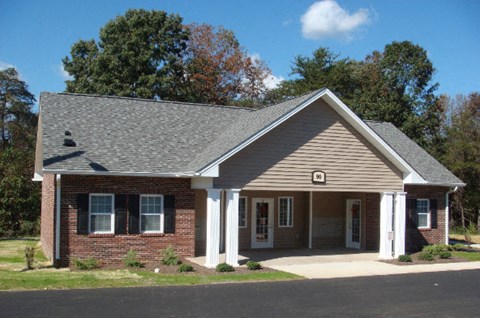 a brick building with a porch and a grey roof