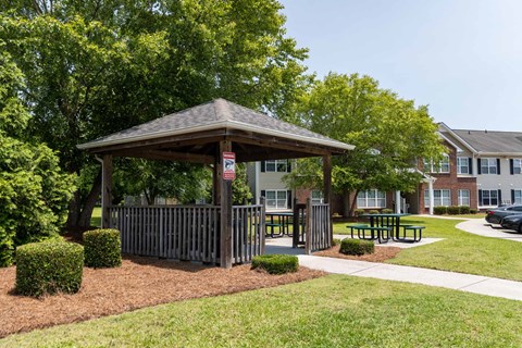 A gazebo is surrounded by bushes and a fence.