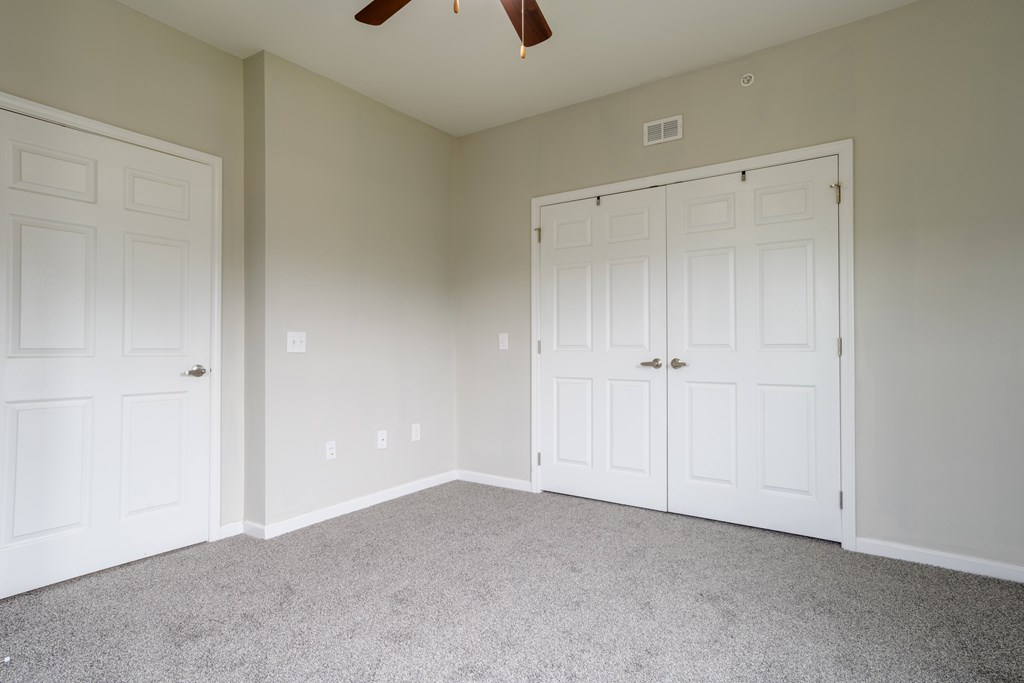 Bedroom with double-door closet, plush carpeting, and neutral wall color, perfect for versatile decor at Cedar Terrace Apartments Hendersonville,  28792