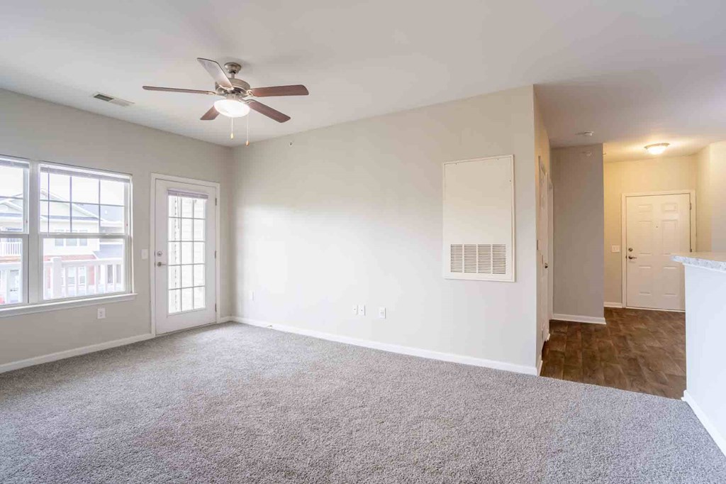Open living area with ceiling fan, plush carpet, and view into hallway and entry, providing functional flow at Cedar Terrace Apartments Hendersonville, NC 