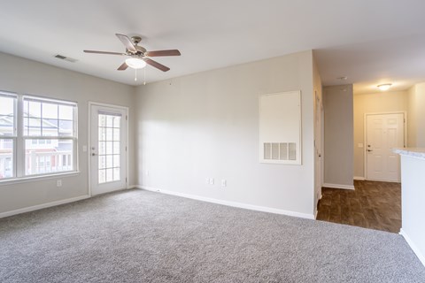 Open living area with ceiling fan, plush carpet, and view into hallway and entry, providing functional flow at Cedar Terrace Apartments Hendersonville, NC