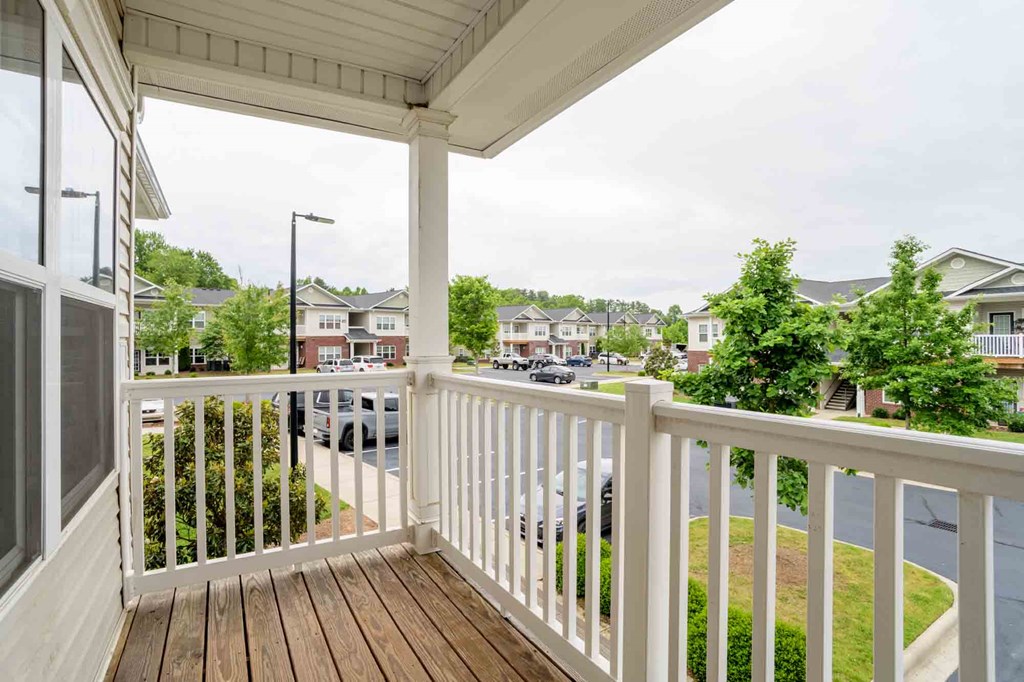 Second-floor private balcony with white railing and scenic views of the Cedar Terrace apartment community and parking area Hendersonville, 28792