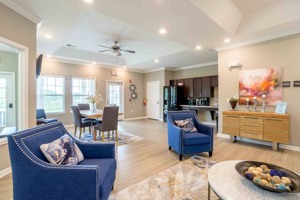 Elegant resident clubhouse with modern furnishings, dining table, lounge seating, and full kitchenette at Cedar Terrace Apartments in 28792