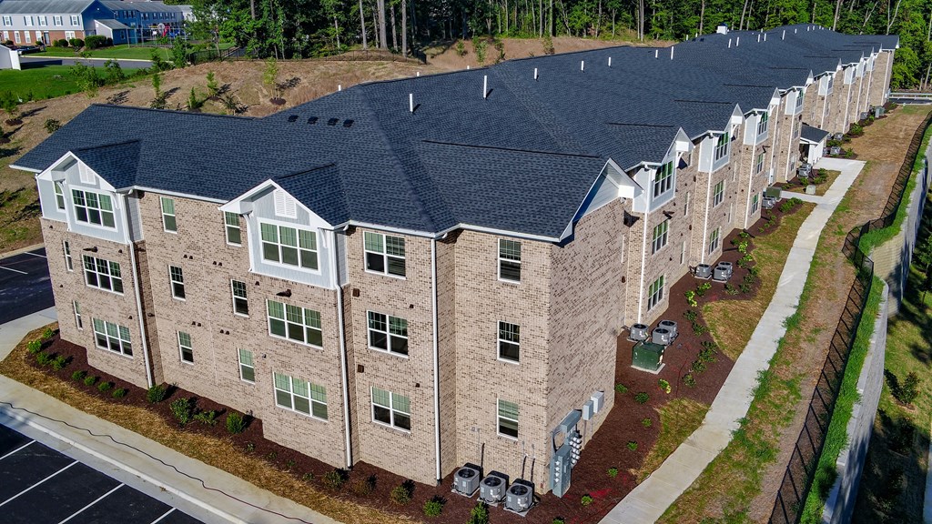 an aerial view of a brick building with a dark roof