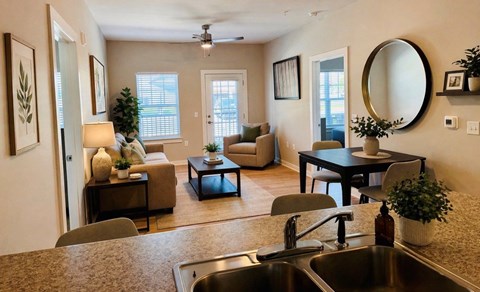 A well-lit, modern kitchen and living room with a dining table and chairs.