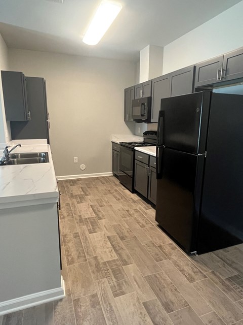 A kitchen with black appliances and a white counter.