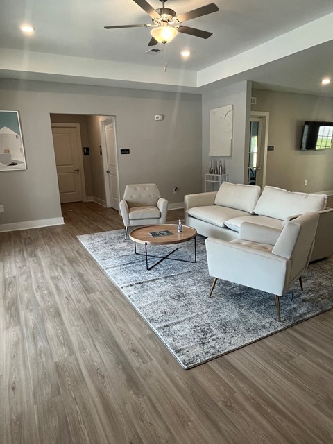 A living room with a white sofa, a white armchair, and a round coffee table.