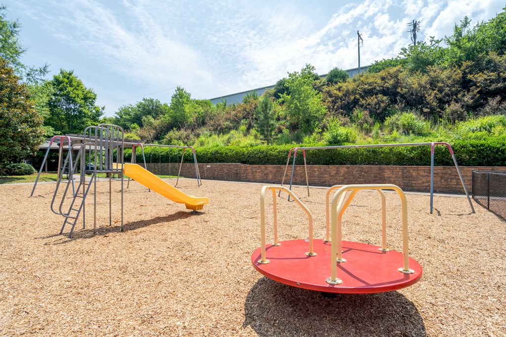 A playground with a red and yellow swing set and a yellow slide.