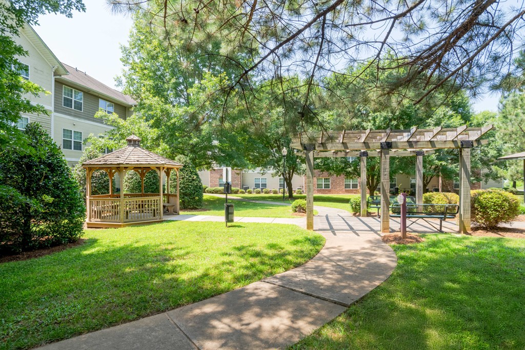A gazebo is located in a grassy area with a wooden pergola.