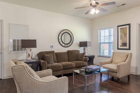 A living room with a brown couch, two chairs, and a coffee table.