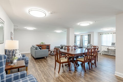 A well-lit living room with a dining table and chairs.