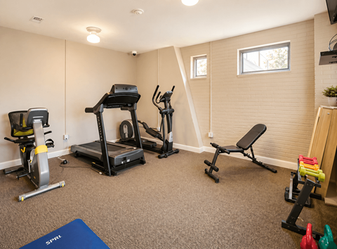 A home gym with a treadmill, exercise bike, and weights.