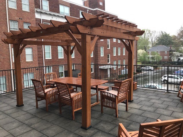 a patio with a table and chairs under a wooden structure