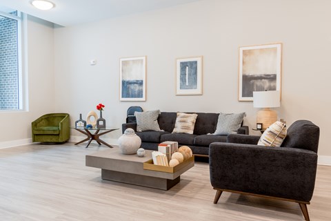 A living room with a grey couch, a green armchair, a wooden coffee table, and two framed pictures on the wall.