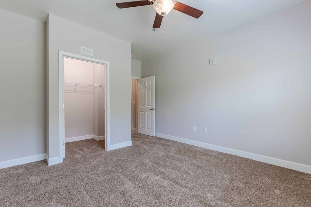 A room with a ceiling fan and carpeted floor.