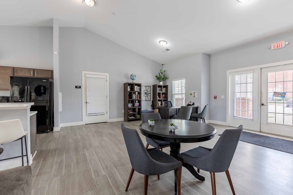 A dining room with a round table and grey chairs.