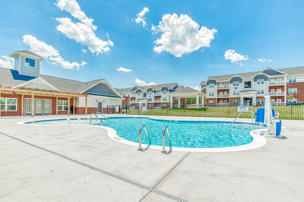 A swimming pool in a residential area with a blue sky and clouds.