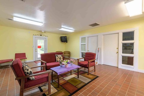 A living room with a purple table and red chairs.
