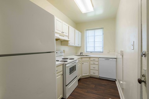 A kitchen with white appliances and wooden floors.at Kinston Oaks Apartments, Kinston, NC