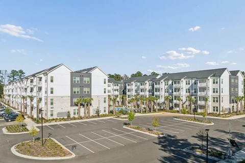 A parking lot in front of a white apartment building.