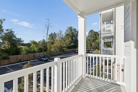 A white balcony with a view of a street and trees.