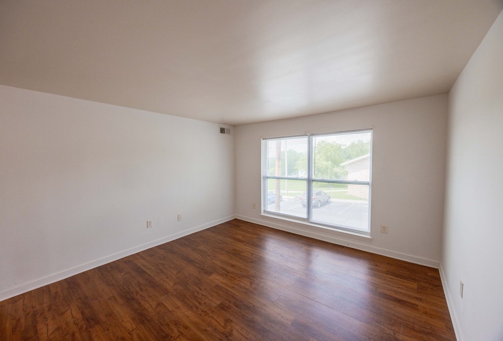 Empty room with wooden floors and a window.