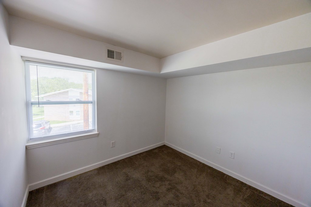 A room with a window and carpeted floor.