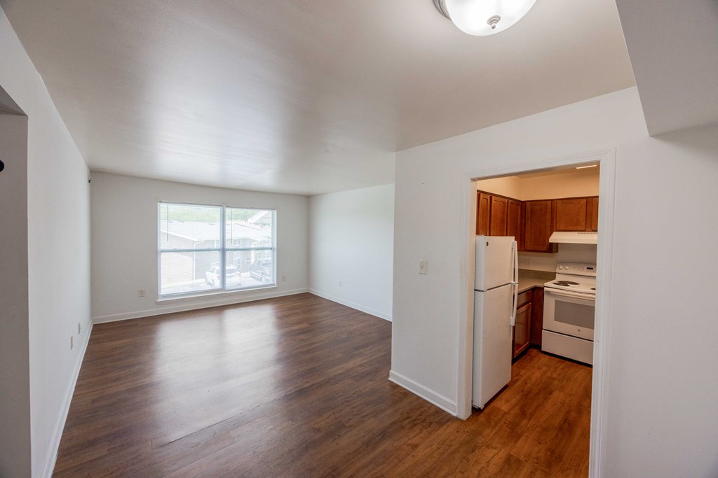 A large empty room with a kitchenette in the corner.