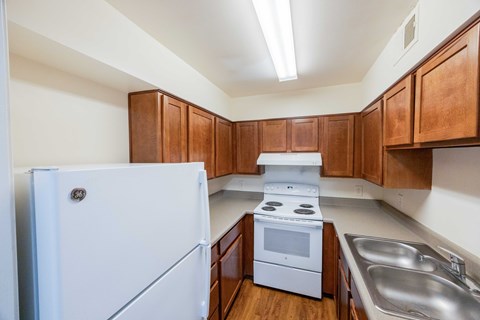 A white refrigerator is in a kitchen with wooden cabinets.