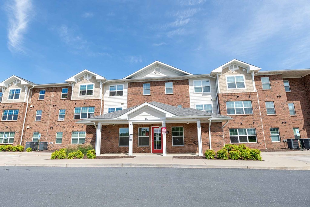 A large brick building with a red door in front. at Mountain Laurel III Apartments, Staunton, VA