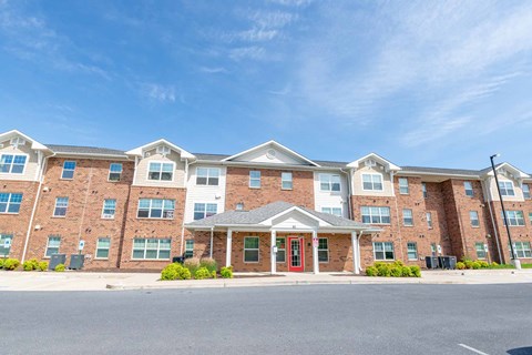A large brick apartment building with a red door in front.