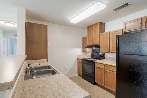 A kitchen with black appliances and wooden cabinets.