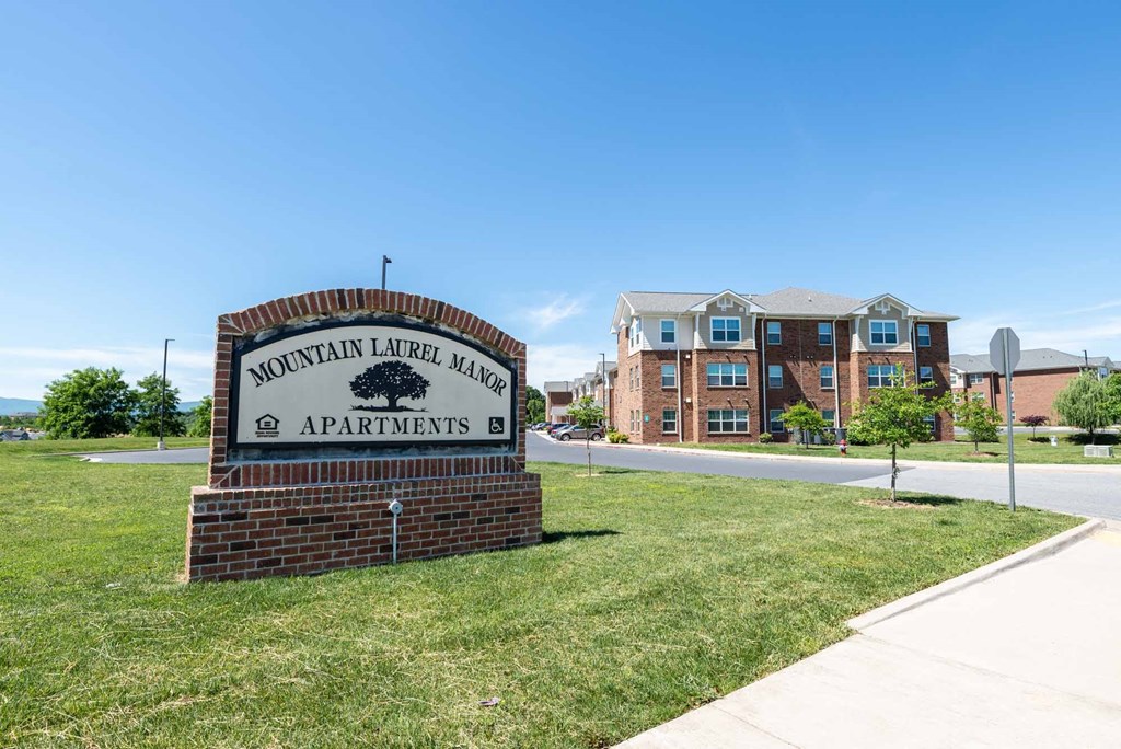 A sign for Mountain Laurel Manor Apartments stands in front of a building. at Mountain Laurel III Apartments, Staunton, VA, 24401