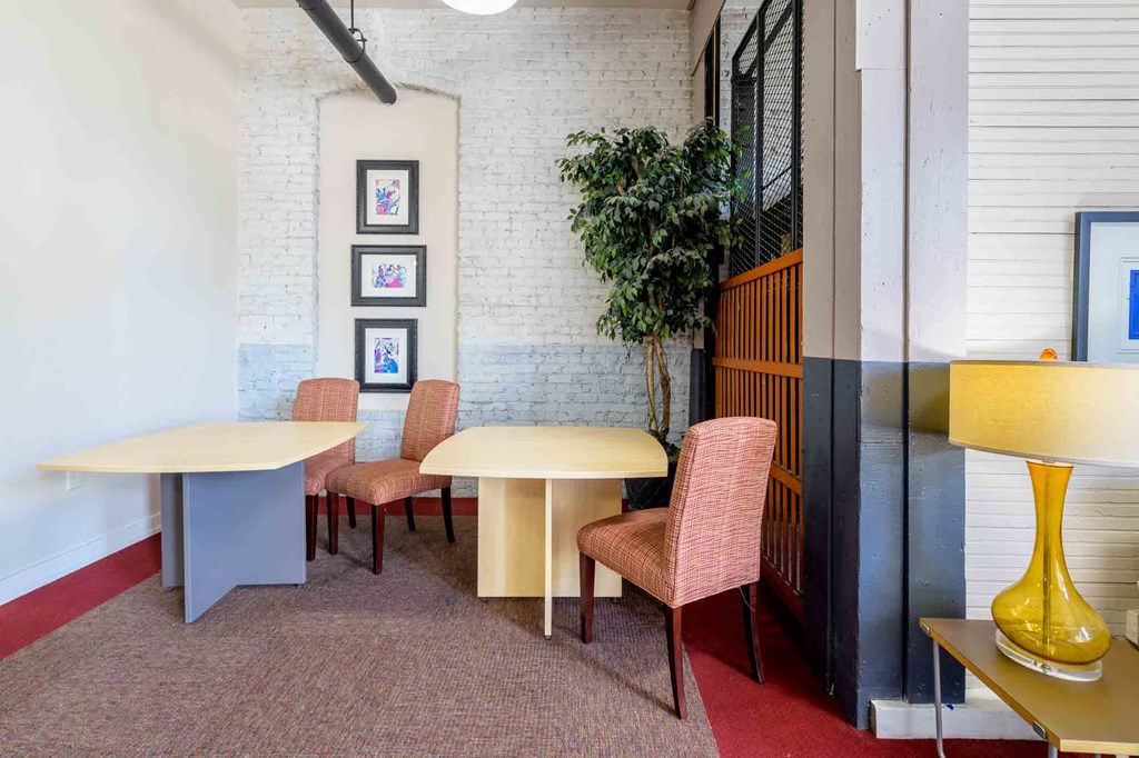 A room with a white brick wall and a table with chairs at Nantucket Lofts Apartments, Kinston, NC, 28501