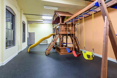 A play area with a slide, swings, and a jungle gym.