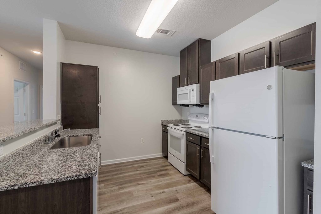 A kitchen with a white refrigerator, white oven, and white microwave.