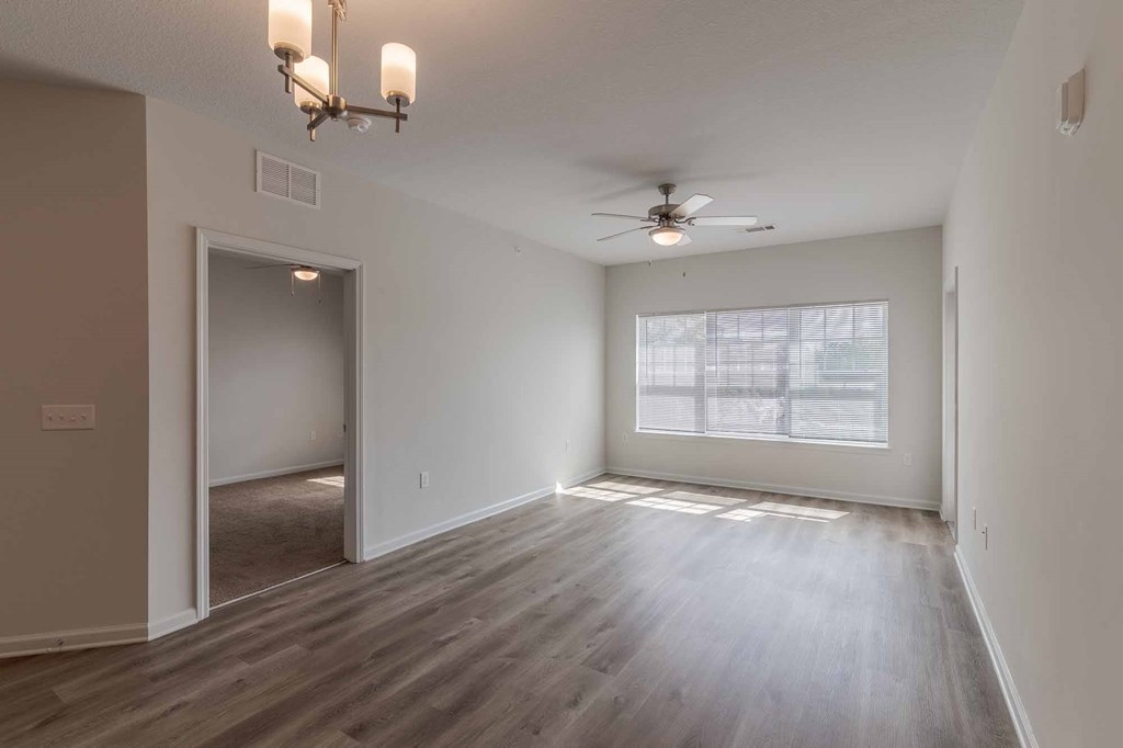 A room with a ceiling fan and a large window.