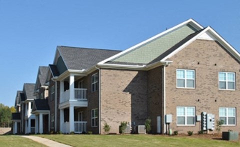 a row of brick apartment buildings on a lawn