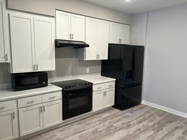 a kitchen with white cabinets and a black refrigerator