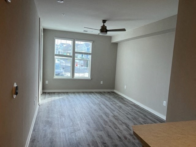 an empty living room with a ceiling fan and a window