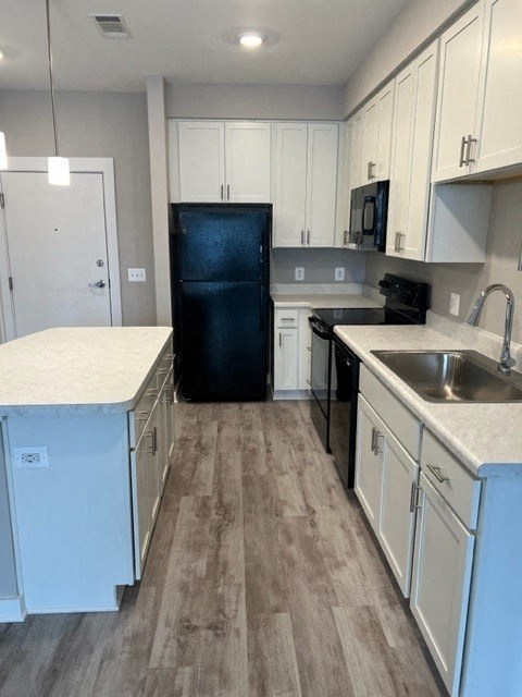 a kitchen with white cabinets and a black refrigerator
