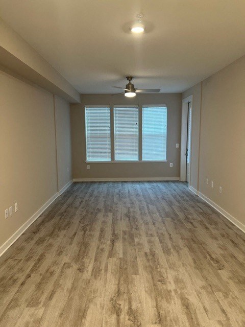 an empty living room with wood floors and a ceiling fan