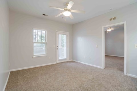 A room with a ceiling fan and carpeted floor.