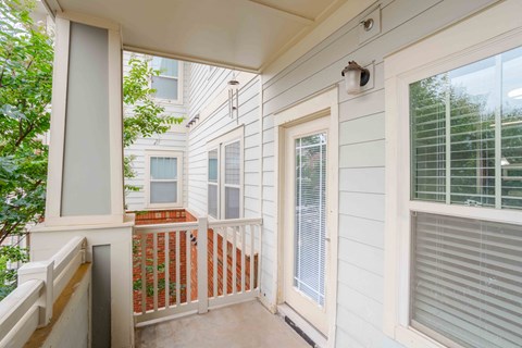 A balcony with a white door and a window with blinds.